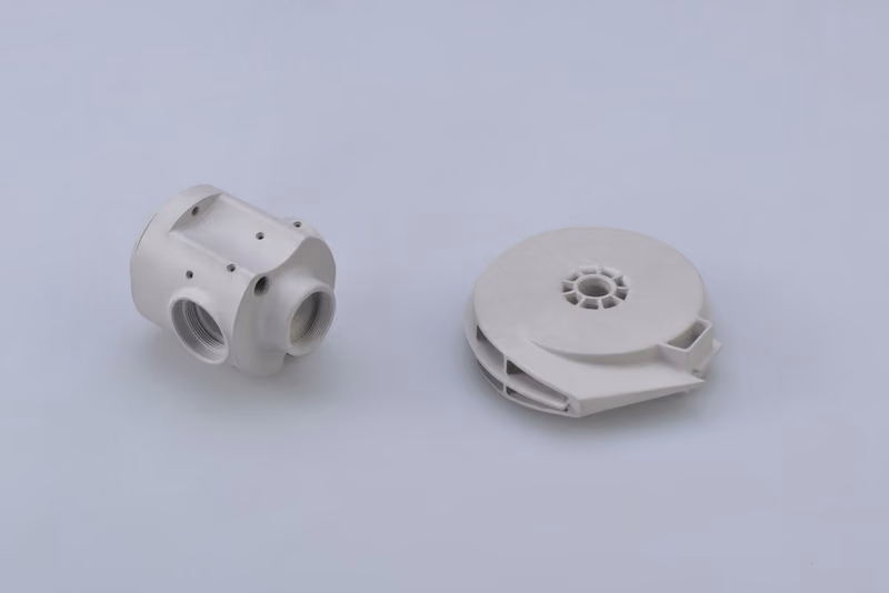 Two white molded housings, a ported valve body and a ribbed impeller cover